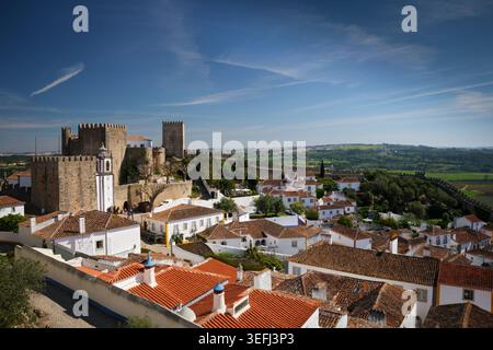 Visitez Obidos au Portugal pour voir son magnifique château médiéval surplombant des maisons traditionnelles et des collines verdoyantes en arrière-plan. Banque D'Images