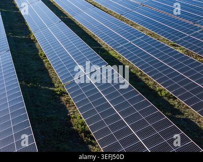 La vue aérienne montre de nombreux panneaux solaires dans une zone rurale produisant de l'électricité propre à partir de la lumière du soleil. Cela met en valeur la technologie des énergies renouvelables. Banque D'Images