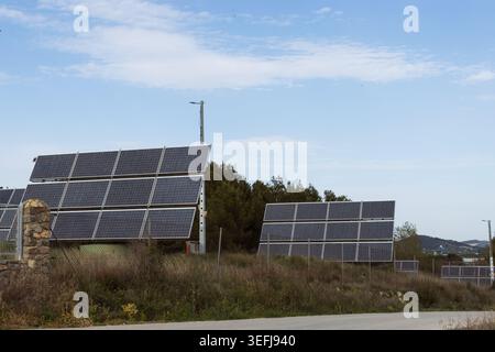 Plusieurs panneaux solaires debout sur une colline herbeuse, capturant la lumière du soleil pour la production d'énergie propre, symbolisant un engagement envers les ressources renouvelables Banque D'Images
