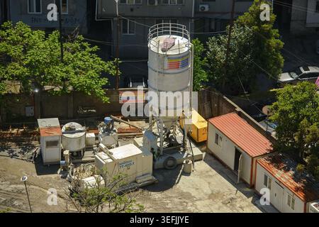 Batumi, Géorgie - 7 mai 2026 : zone industrielle avec réservoir de stockage de ciment, machines Soilmec, et conteneurs de logement temporaire par une journée ensoleillée. Banque D'Images