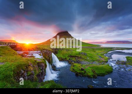 Magnifique coucher de soleil brille sur Kirkjufell montagne volcanique verte luxuriante avec cascade coulante et ciel spectaculaire vif pendant l'été à Snaefellsnes, Icela Banque D'Images