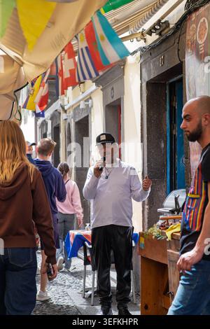 Funchal Madère 9 mai 2026 Un homme portant une casquette de baseball noire, une chemise blanche à manches longues et un pantalon noir chante dans un microphone Banque D'Images