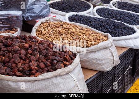 Abricots séchés, noix et raisins secs noirs exposés dans de grands sacs au Siab Bazaar à Samarcande. Scène de marché traditionnelle idéale pour la nourriture, les voyages, et Banque D'Images