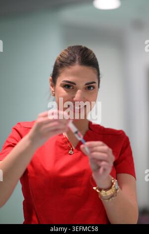 Infirmière souriante préparant une seringue de vaccin en uniforme clinique fournissant des soins de santé professionnels et des soins aux patients Banque D'Images