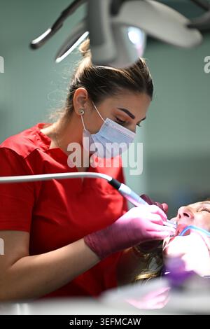 Hygiéniste dentaire féminine portant masque et gants traitant le patient dans la clinique dentaire moderne Banque D'Images