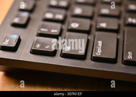 Vue de dessus inclinée latérale Macro gros plan clavier d'ordinateur noir mise en surbrillance de la touche Tab sur les arrière-plans techniques flous Banque D'Images