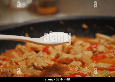 Cuisson du poulet avec des épices dans un cadre de cuisine Banque D'Images