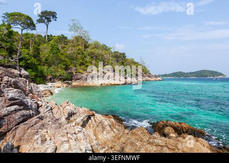La côte rocheuse rencontre les eaux turquoises à la plage secrète de Koh Lipe. Une végétation luxuriante encadre la crique tranquille et isolée. Banque D'Images