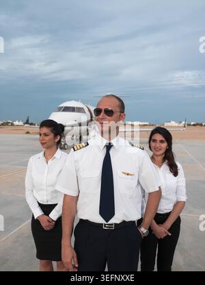 Équipe d'affaires du moyen-Orient et pilote posant en toute confiance devant un jet privé sur le tarmac de l'aéroport Banque D'Images