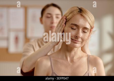 Femme d'âge moyen recevant un massage de la tête pour thérapie de bien-être Banque D'Images