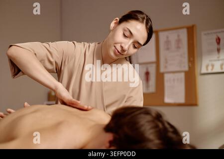 Thérapeute femme adulte appliquant une pression manuelle pour la récupération du dos Banque D'Images