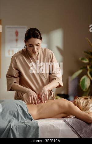 Thérapeute femme adulte appliquant la pression pendant la séance de soins du dos Banque D'Images