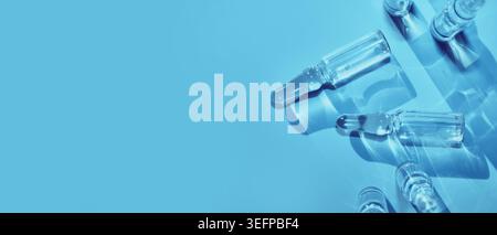 Ampoules en verre transparent présentant des concepts de médicaments ou de vaccins sur fond bleu vif Banque D'Images