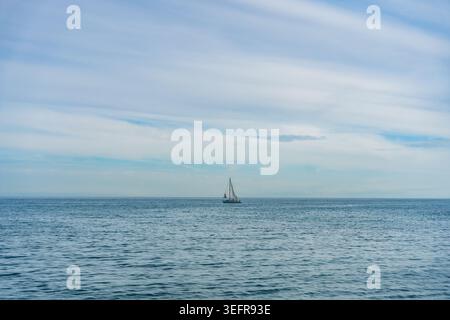 Voilier solitaire sur l'horizon bleu calme de la mer Banque D'Images