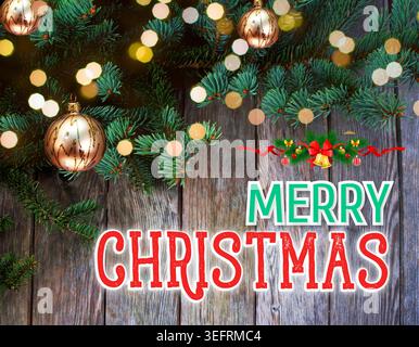 Modèle de carte de voeux joyeux Noël avec texte de typographie festif, branches de pin de Noël décorées, boules dorées et lumières bokeh chaudes Banque D'Images