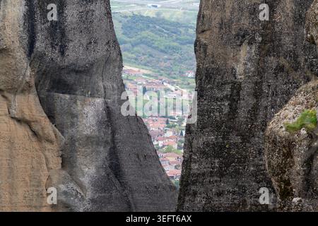 Une perspective unique des maisons au toit rouge du village de Kastraki encadrées par l'écart imposant et étroit de deux anciennes formations rocheuses dans les Météores. Banque D'Images