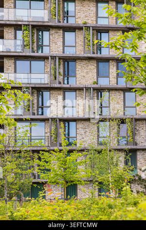 Immeuble d'appartements en briques moderne encadré par des arbres et des jardins de balcon dans une banlieue verdoyante d'Ede, pays-Bas. Accent mis sur une vie urbaine durable Banque D'Images