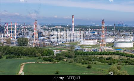 Une photo de paysage grand-angle d'une installation de traitement chimique industrielle à grande échelle et de réservoirs de stockage de pétrole sous un ciel bleu, entouré d'un champ vert Banque D'Images