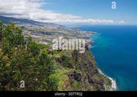 Funchal, Madère, 12 mai 2026. Cabo Girao Skywalk vue panoramique sur une ville côtière construite sur des collines verdoyantes et des falaises surplombant l'océan bleu. Banque D'Images