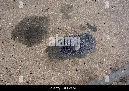 Une tache d'huile moteur sur une route asphaltée provenant d'une voiture en panne. Banque D'Images
