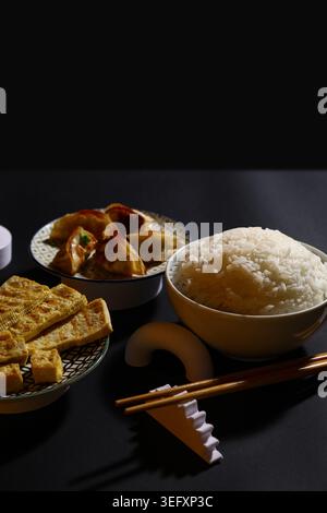 Délicieux plats chinois et baguettes sur fond sombre Banque D'Images