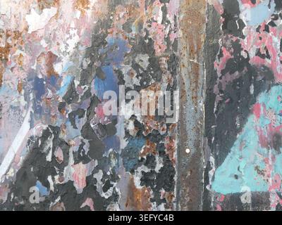 Gros plan abstrait d'un mur métallique altéré avec de la peinture écaillée, de la rouille et de la corrosion. Les couches écaillées révèlent les textures grunge en bleu, rose, sarcelle, Banque D'Images