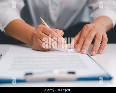 Gros plan mains signant le formulaire sur le presse-papiers avec un stylo doré, montrant la signature du contrat, l'approbation du document, les documents juridiques, le processus financier, veri. affaires Banque D'Images