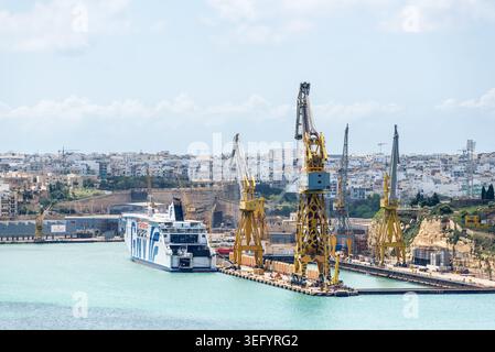 Valette, Malte – 16 mai 2025 : un grand ferry de passagers accosté à côté de grues industrielles au port de Malte Freeport dans le port de la Valette, présentant le transp maritime Banque D'Images