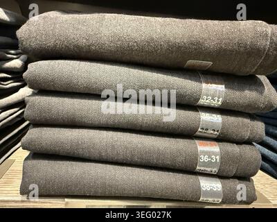 Pile de jeans en denim pliés en étalage de détail montrant différentes tailles et étiquettes. Photo mobile Banque D'Images