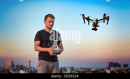 Homme pilotant un drone au-dessus de la ville au coucher du soleil Banque D'Images