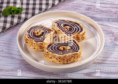 Trois tranches de petits pains sucrés traditionnels, peut-être un délice turc, disposées sur une assiette blanche. Dessert recouvert de graines de sésame avec garniture de noix. Rustique w Banque D'Images
