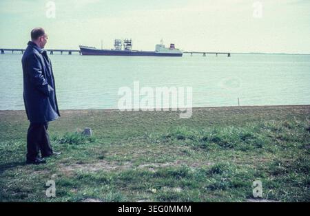 Mann steht am Strand von Wilhelmshaven mit auf den Jadebusen und Ölpier. / Un homme se tient sur la plage de Wilhelmshaven, regardant vers la baie de Jade et la jetée de carburant. *Aufnahmedatum geschätzt/date estimée* snapshot-Photography/H.Seeliger *** homme debout sur la plage de Wilhelmshaven, regardant vers la baie de Jade et la jetée de carburant Un homme se tient sur la plage de Wilhelmshaven, regardant vers la baie de Jade et la jetée de carburant date estimée snapshot photographie H Seeliger Banque D'Images