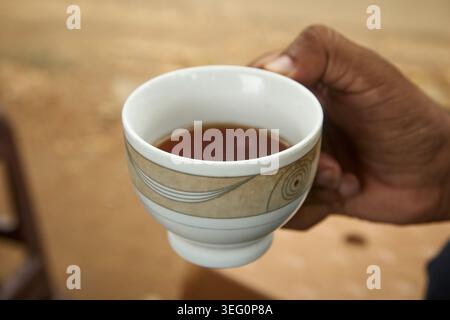 tasse en céramique blanche de thé chaud, tenue à la main, vue latérale en gros plan avec espace de copie, concept traditionnel de boisson de pause du matin Banque D'Images