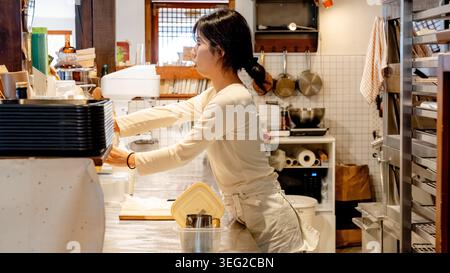Un barista dévoué prépare le café derrière le comptoir dans un café sud-coréen confortable, mettant en valeur l'atmosphère animée et les détails complexes de t Banque D'Images