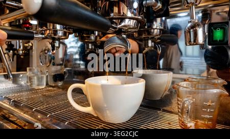 Gros plan sur un espresso en cours de préparation dans un café sud-coréen animé, mettant en évidence le processus d'extraction riche et aromatique et l'ambiance chaleureuse Banque D'Images