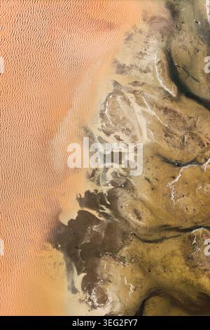 Les motifs colorés de la terre forment un fond naturel abstrait vu d'en haut, avec des ondulations de sable et des taches minérales créant une texture aérienne saisissante i. Banque D'Images