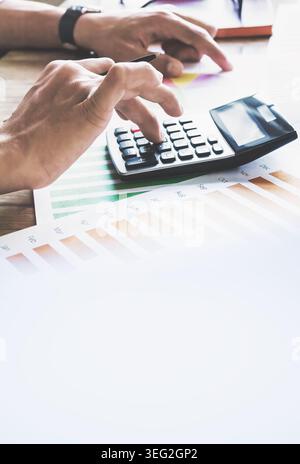 Les mains utilisent la calculatrice sur les graphiques financiers. Personne concentrée sur les tâches de budgétisation ou de comptabilité. Image idéale pour la finance, les affaires ou les thèmes économiques Banque D'Images
