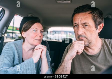 Couple d'âge moyen ayant une conversation sérieuse en étant assis dans une voiture garée, focalisation sélective Banque D'Images
