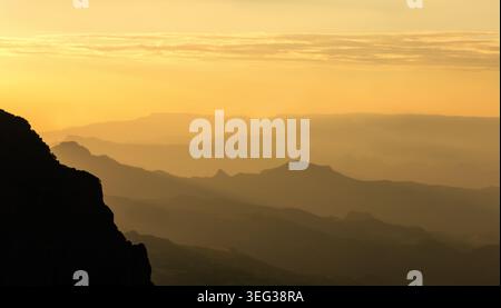 Un coucher de soleil doré brumeux à couper le souffle projetant des silhouettes superposées à travers les pics accidentés et les vallées des montagnes Simien., Éthiopie. Banque D'Images