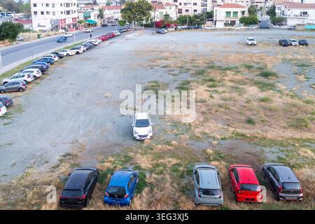 Larnaca, Chypre, 17 mai 2026, vue panoramique à grand angle d'un grand parking en terre battue dans la ville avec plusieurs voitures garées sur de l'herbe sèche. Banque D'Images