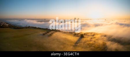 Vue panoramique par drone de Prague au lever du soleil en automne avec un brouillard matinal dense, la tour V et la tour de télévision Zizkov au-dessus de la brume. Banque D'Images