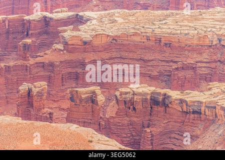 Des formations rocheuses rouges massives et des parois profondes du canyon remplissent le paysage désertique sous la lumière du soleil. Banque D'Images