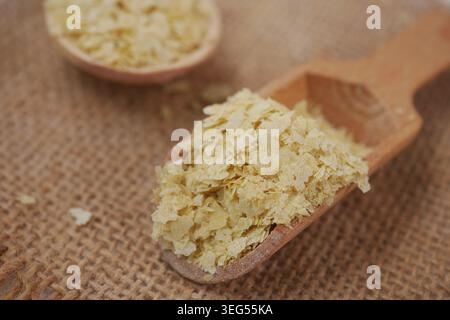 Levure nutritionnelle dans une cuillère en bois sur fond de toile de jute Banque D'Images