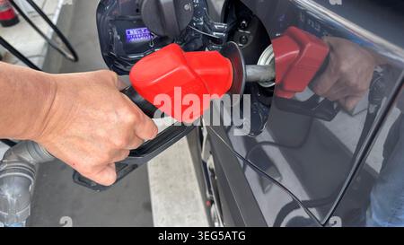 Kasukabe, Saitama, Japon avril 28,2026 Une personne utilise un pistolet à essence rouge ordinaire pour faire le plein d'une voiture grise à une station ENEOS EneJet en libre-service Banque D'Images