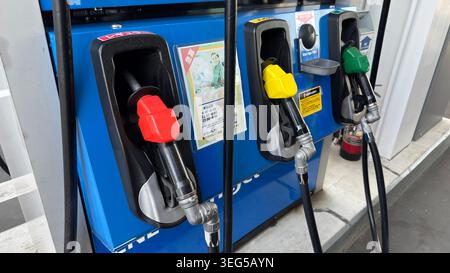 Les injecteurs de carburant en libre-service à code couleur, y compris le rouge pour l'essence ordinaire et le jaune pour l'essence à indice d'octane élevé, reposent dans leur berceau à une station EneJet ENEOS Banque D'Images