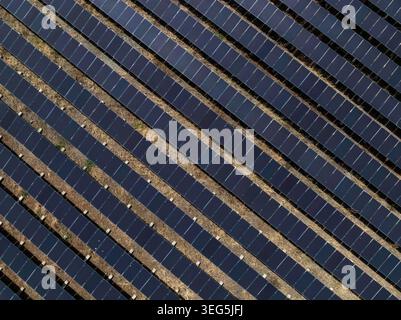 Vue à angle élevé de plusieurs rangées de panneaux solaires utilitaires disposés selon un motif diagonal répétitif pour la production d'énergie propre. Banque D'Images