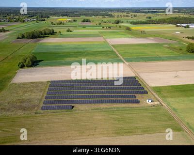 Vue aérienne de rangées de panneaux solaires photovoltaïques parmi les champs dans la région de Mazowsze en Pologne Banque D'Images