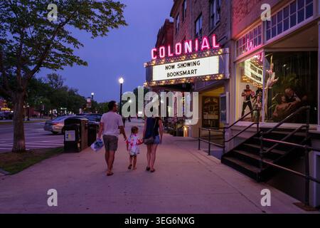 La famille passe devant un cinéma vintage au crépuscule Banque D'Images