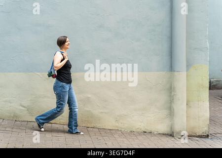 Femme blonde souriante marchant avec un sac d'épicerie en maille plein de légumes frais Banque D'Images