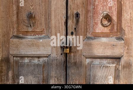 Deux portes en bois se tiennent fermées et usées, montrant des signes d'âge. Un verrou et une chaîne les maintiennent ensemble. Les portes ont un appel rustique, mis dans un env simple Banque D'Images